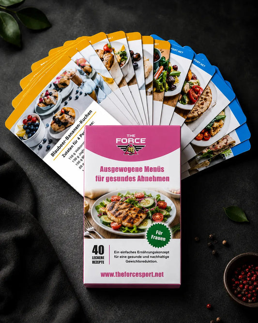 A boxed card deck titled "THE FORCE" with the German text "Ausgewogene Menüis für gesundes Abnehmen" is displayed in front of a fanned-out set of recipe cards on a dark textured surface. The box is pink and white with a salad photo, and the cards show colorful food and recipe imagery.