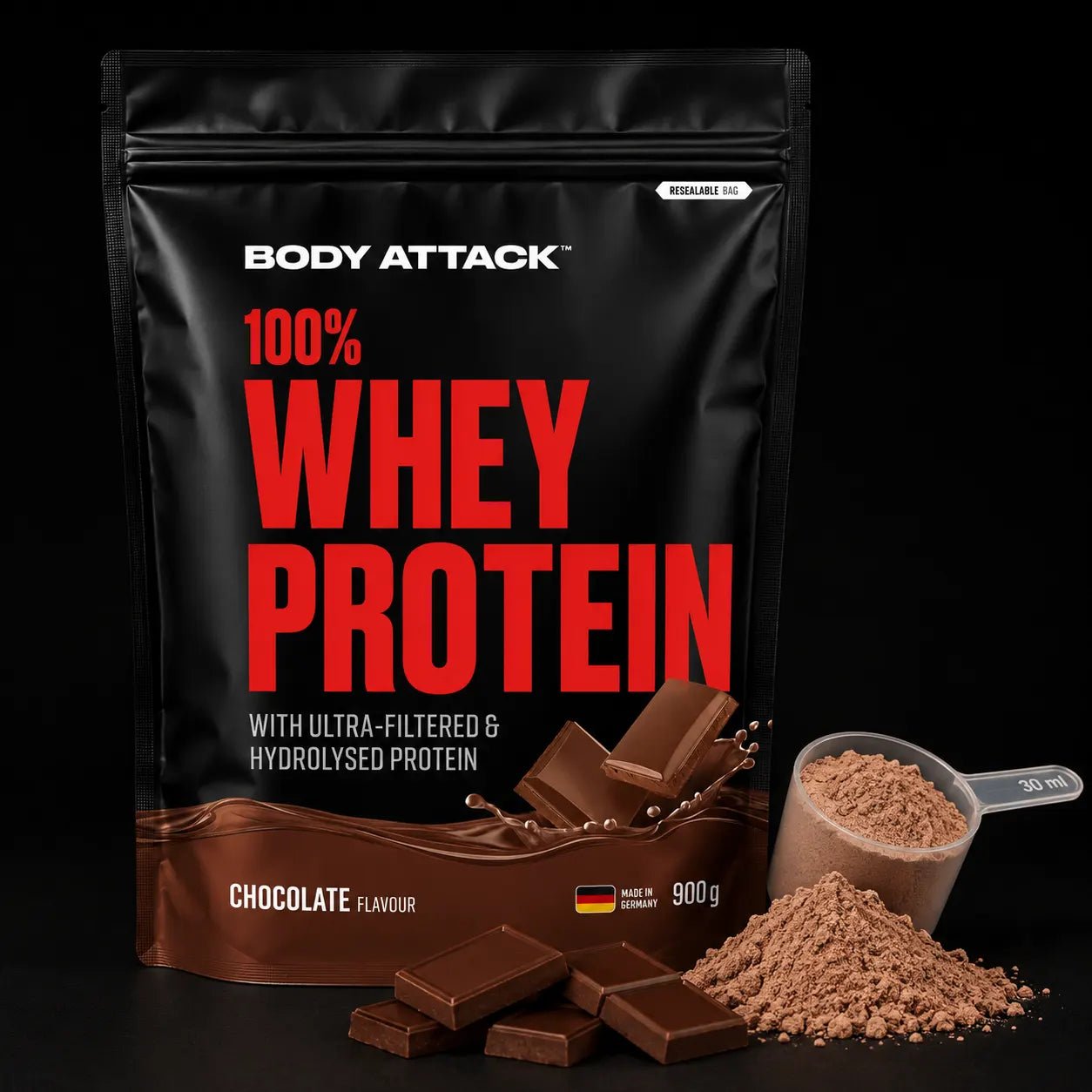 A 900 g bag of Body Attack 100% Whey Protein in Chocolate Flavour, displayed alongside chocolate pieces, a scoop of powder, and a pile of powder on a black background.