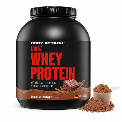  Body Attack 100% Whey Protein in Chocolate Brownie flavour, shown on a white background with a scoop and pile of brown powder in front.