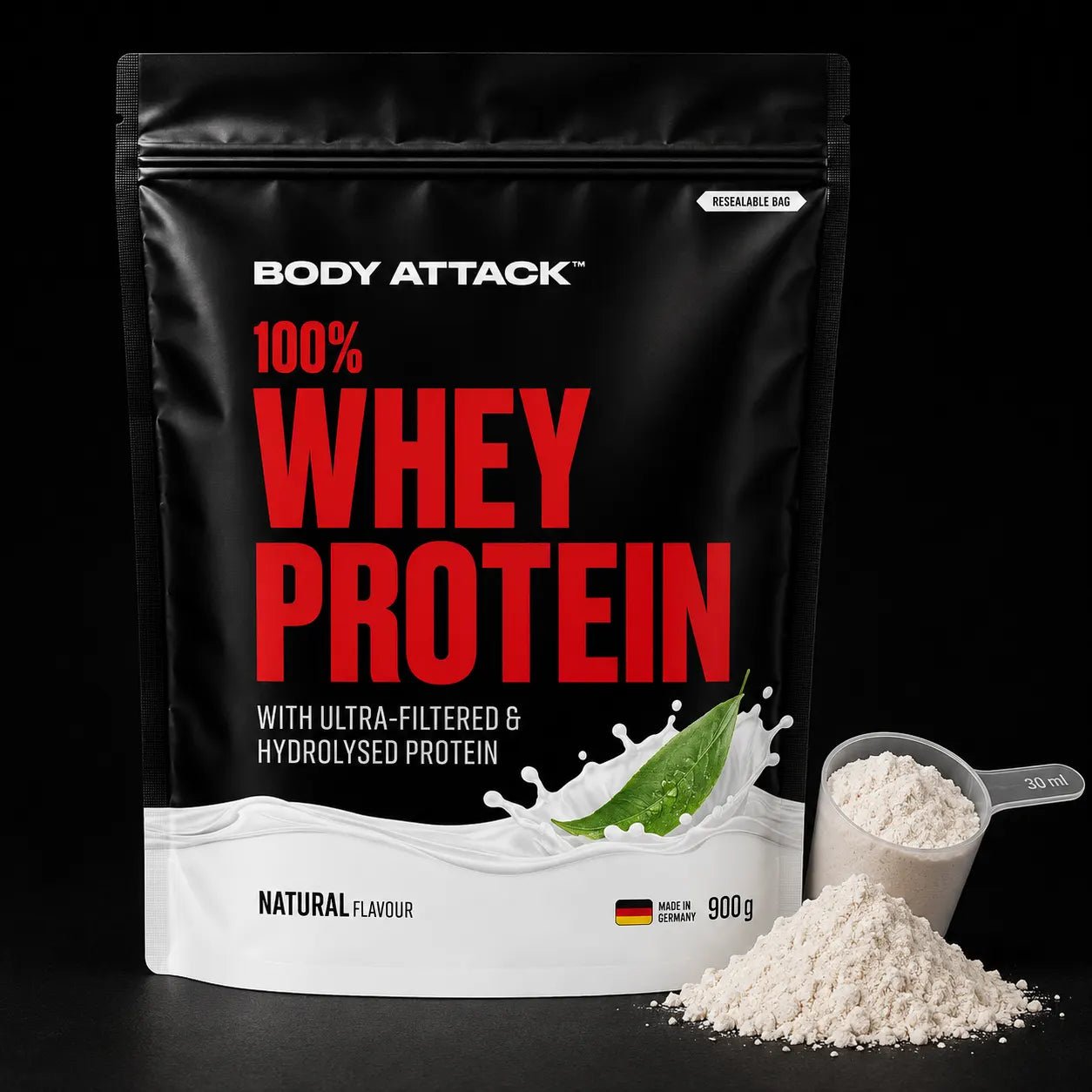 Body Attack 100% Whey Protein powder in a 900g resealable stand-up pouch, shown on a black background with a scoop and pile of white powder in front.